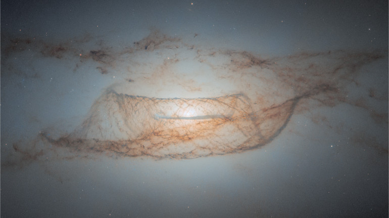 Телескоп Хаббл зазнімкував далеку галактику, окутану пилом: вона має яскраве біле ядро