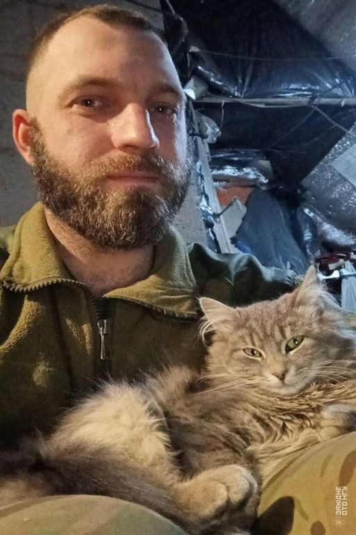 A military man holds a cat in his arms
