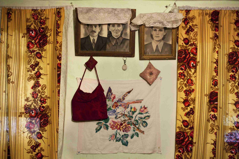 Стіна в будинку Зоре Курсутової, 82, з портретом її та її батьків і Кораном у Новоселівському, Крим, липень 2013 року. Фото Еміне Зіятдінової, представлене на виставці Ломикамінь