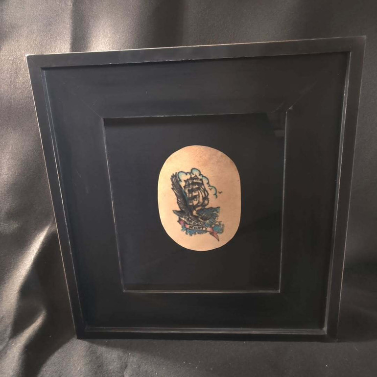 Фрагмент із татуюванням на шкірі померлого у рамці