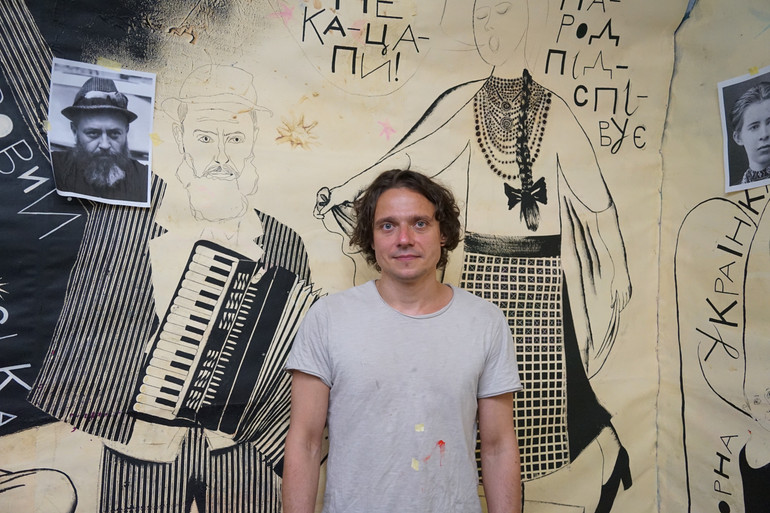 Микола Коломієць біля ще незавершеного панно для Літературного ярмарку