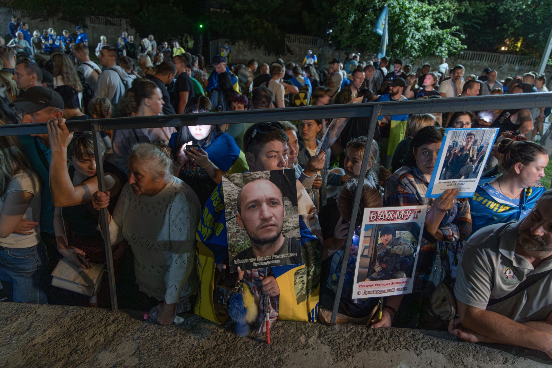 Родини з фотографіями їхніх рідних захисників зустрічають військових з полону