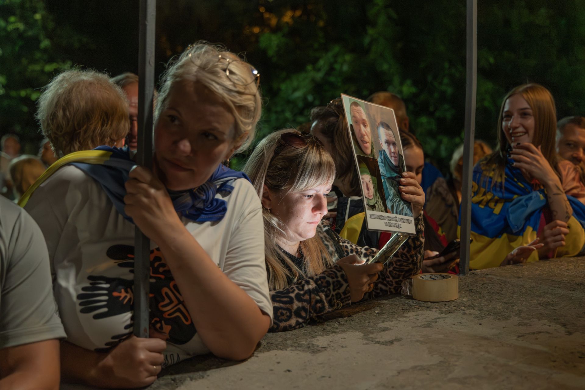 Родини з фотографіями їхніх рідних захисників зустрічають військових з полону