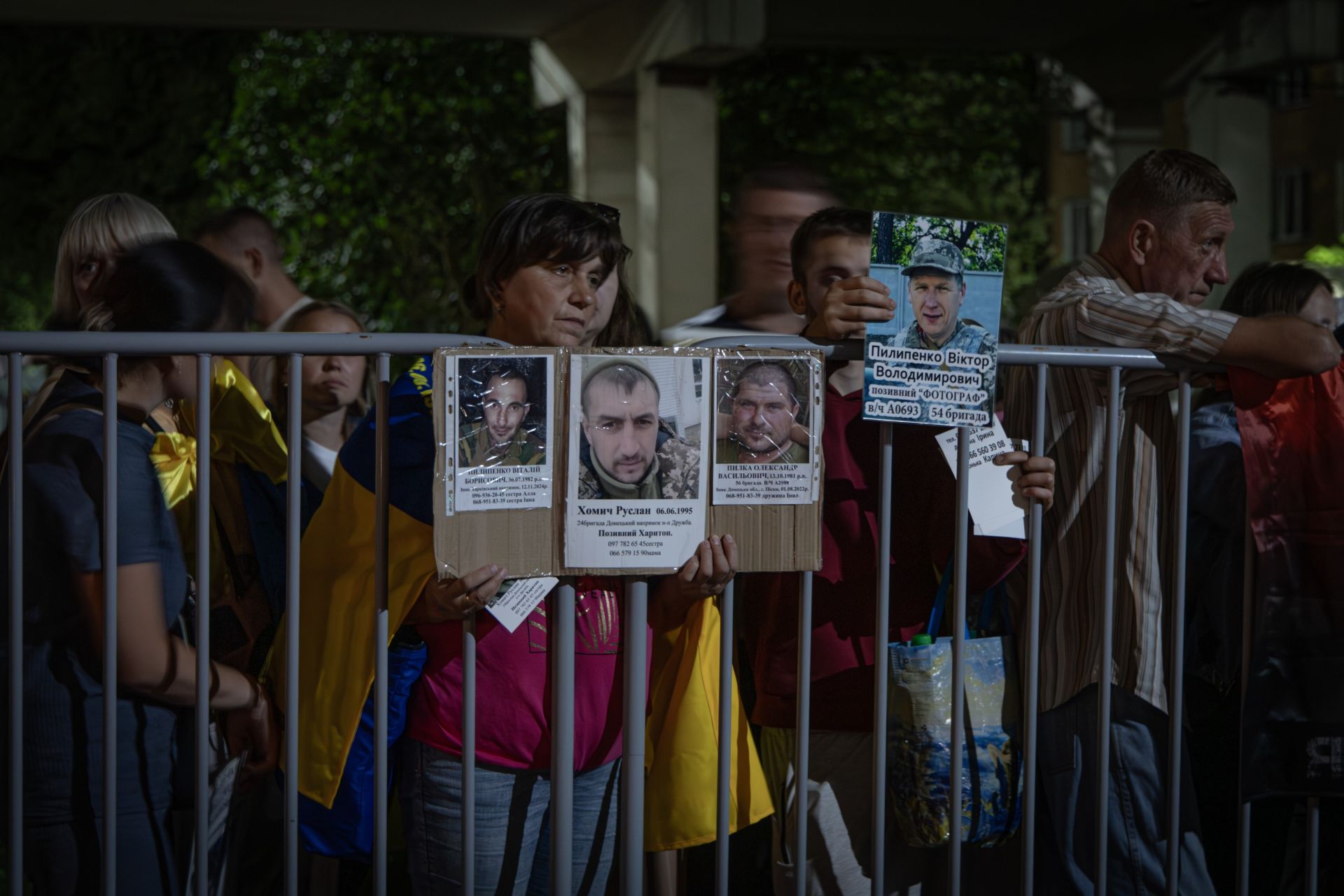 Родини з фотографіями їхніх рідних захисників зустрічають військових з полону